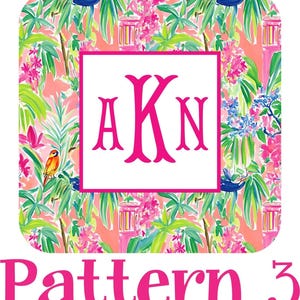 The image is a collage of various tropical floral patterns, including palm leaves, flowers, and birds, with a pink monogrammed logo in the center.