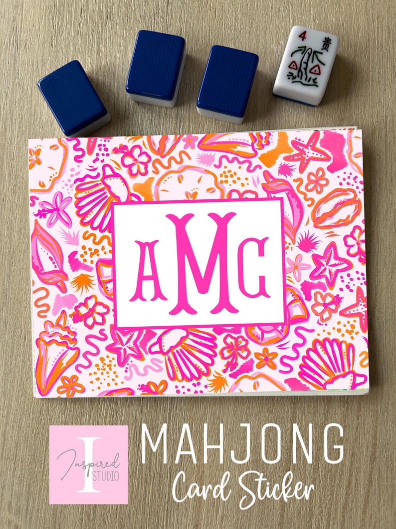 May include: A rectangular sticker featuring a vibrant pattern of pink and orange seashells, starfish, and flowers on a light background. A central white rectangle contains the hot pink monogram letters AMG. Four mahjong tiles are placed above.
