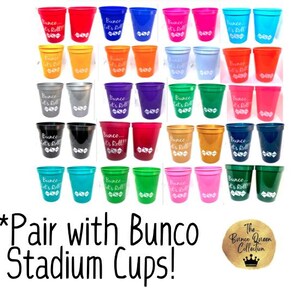 May include: A set of 24 colorful plastic stadium cups with the text "Bunco It's Roll!" printed on them. The cups are arranged in rows of four, with each row featuring a different color. The cups are perfect for a Bunco party or game night.