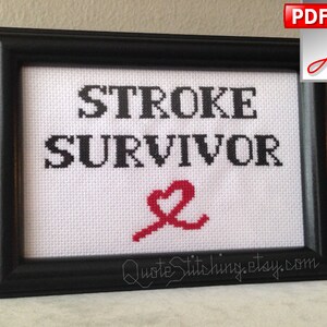 Puede incluir: Bordado enmarcado en negro con tela blanca y texto negro que dice "STROKE SURVIVOR" con un símbolo de corazón rojo.