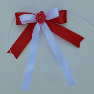 May include: A red and white satin bow with a pink fabric flower in the center.