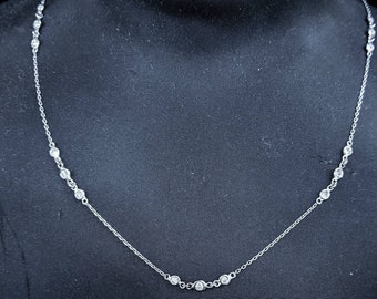 May include: A silver chain necklace with small round clear stones. The necklace is on a black mannequin.