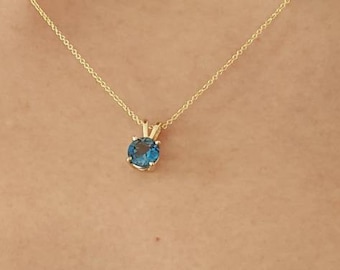 May include: A delicate gold chain necklace with a small, round blue gemstone pendant.