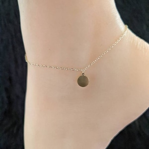 May include: A gold chain ankle bracelet with a small round charm.