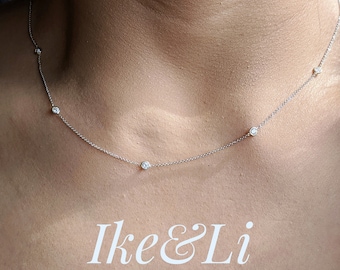 May include: A delicate silver chain necklace with five small, clear gemstones. The necklace is worn by a person, but the focus is on the necklace itself. The text "Ike&Li JEWELRY" is visible at the bottom of the image.