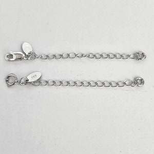 May include: Two silver-colored necklace extenders. Each extender features a chain of small, oval links. One has a lobster clasp and a tag that reads "925". The other has a spring ring clasp and a similar tag. Jewelry accessories.