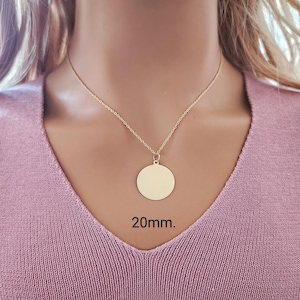 Puede incluir: Un collar de color dorado con un colgante circular de superficie lisa y plana. El colgante cuelga de una cadena delicada. El texto 20mm. es visible debajo del colgante, indicando el di&aacute;metro del dije circular.