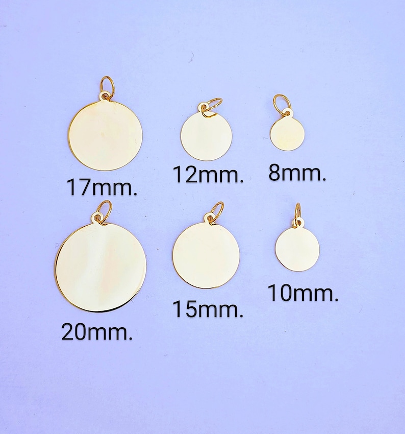 Puede incluir: Seis dijes circulares de metal de color dorado con anillas adjuntas, dispuestos en dos filas. Los dijes est&aacute;n etiquetados con sus di&aacute;metros respectivos: 17mm, 12mm, 8mm, 20mm, 15mm y 10mm. Cada dije tiene una superficie lisa y reflectante.