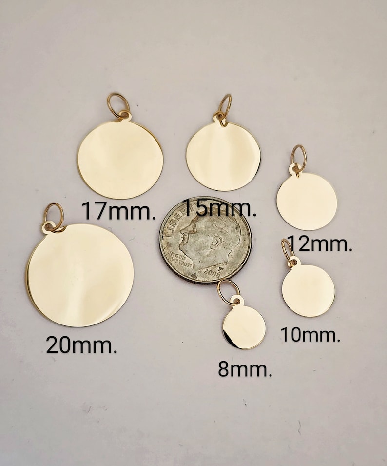Puede incluir: Seis dijes met&aacute;licos circulares de color dorado con anillas, dispuestos alrededor de una moneda de diez centavos de EE. UU. Los dijes est&aacute;n etiquetados con los tama&ntilde;os 20mm, 17mm, 15mm, 12mm, 10mm y 8mm, indicando sus di&aacute;metros para proyectos.