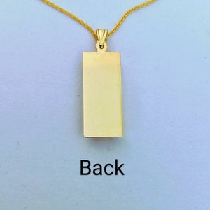 Op de afbeelding: Een goudkleurige rechthoekige hangerketting met bijpassende ketting. De hanger heeft een glad, leeg oppervlak met het woord "Back" in het zwart gedrukt. De ketting wordt gepresenteerd tegen een lichte achtergrond.