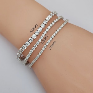 May include: Three silver tennis bracelets with clear cubic zirconia stones. The bracelets are 2.0mm, 2.5mm, and 4.0mm in width.
