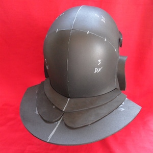May include: A black foam helmet with a layered, scalloped brim. The helmet is marked with numbers and letters.