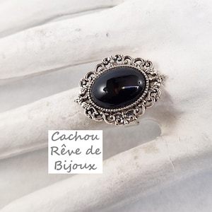 Peut inclure: Une bague en argent avec une pierre ovale noire sertie dans un décor de filigrane.