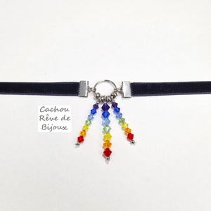 Może przedstawiać: Czarny choker z aksamitu z zawieszką z tęczowych kryształów. Zawieszka wykonana jest z małych, fasetowanych kryształów w kolorach tęczy. Choker jest przymocowany do zawieszki srebrnym pierścieniem i łańcuszkiem.