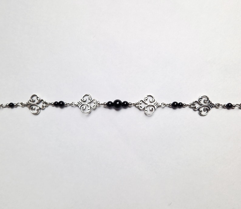 May include: A silver chain bracelet with black beads and decorative silver charms.