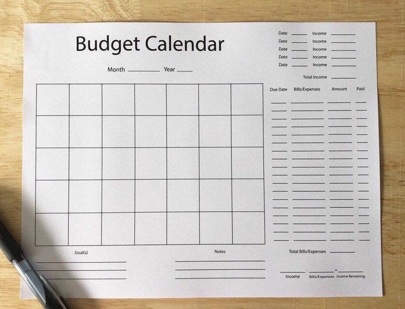 以下が含まれることがあります： 黒い線とテキストが入った白い予算カレンダーシート。「Budget Calendar」というタイトルが上部にあり、月と年のスペースがあります。収入、支出、メモのセクションが含まれています。
