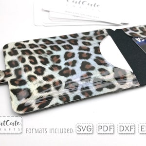 May include: A leopard print card holder with a clear plastic front and a black back. The card holder has a snap closure and is designed to hold credit cards or other small items. The image includes the text "CutCute Crafts" and "Formats Included: SVG PDF DXF EPS".