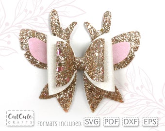 May include: Gold glitter bow with pink felt ears and antlers. The bow is layered with white felt and has a gold glitter finish.  The bow is perfect for a hair accessory or a craft project.