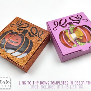 May include: Two small pumpkin-shaped gift boxes with cut-out designs. One box is orange glitter and the other is purple. The boxes are open and show a clear window.
