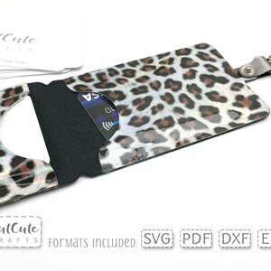 May include: A leopard print card holder with a clear window for displaying a credit card. The holder has a black fabric interior and a silver metal key ring.