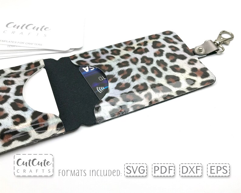 May include: A leopard print card holder with a clear window for displaying a credit card. The holder has a black fabric interior and a silver metal key ring.