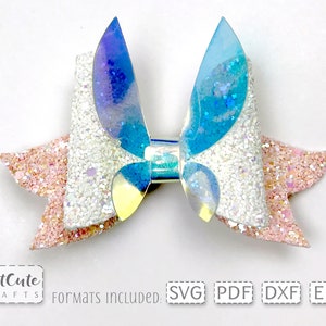 May include: A white and pink glitter bow with iridescent blue and purple accents. The bow is made of fabric and has a layered design. The bow is perfect for adding a touch of sparkle to any outfit.