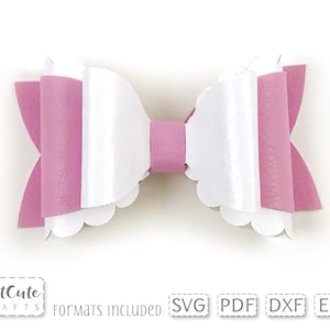 May include: A white and pink layered bow with scalloped edges. The bow is made of felt and is perfect for adding a touch of whimsy to any project.