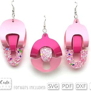 以下が含まれることがあります： ピンクとライトピンクの幾何学的なレイヤー状のイヤリングで、グリッターのアクセントが施されています。イヤリングはアクリル製で、モダンなデザインです。フォーマットに含まれるもの：SVG、PDF、DXF、EPS