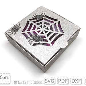 Könnte beinhalten: Eine silberne Glitzerbox mit einem Spinnennetz-Ausschnitt und violetten Glitzerakzenten. Die Box hat vier Spinnen auf der Außenseite. Die Box ist geschlossen und steht auf einer weißen Oberfläche.  "Formate enthalten: SVG PDF DXF EPS"
