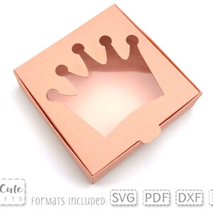 May include: A light pink cardboard box with a crown-shaped cut-out window. The box is open and the window is visible. The text "Formats Included: SVG PDF DXF EPS" is printed on the bottom of the image.
