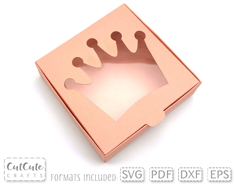 May include: A light pink cardboard box with a crown-shaped cut-out window. The box is open and the window is visible. The text "Formats Included: SVG PDF DXF EPS" is printed on the bottom of the image.