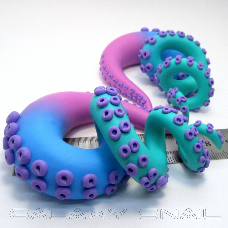 May include: Two handmade polymer clay octopus ear gauges. The gauges are a gradient of pink to blue with purple tentacles.