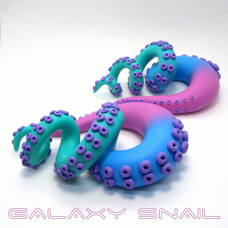 May include: Two galaxy snail earrings, one in pink and blue with a teal swirl, and the other in teal with purple dots.