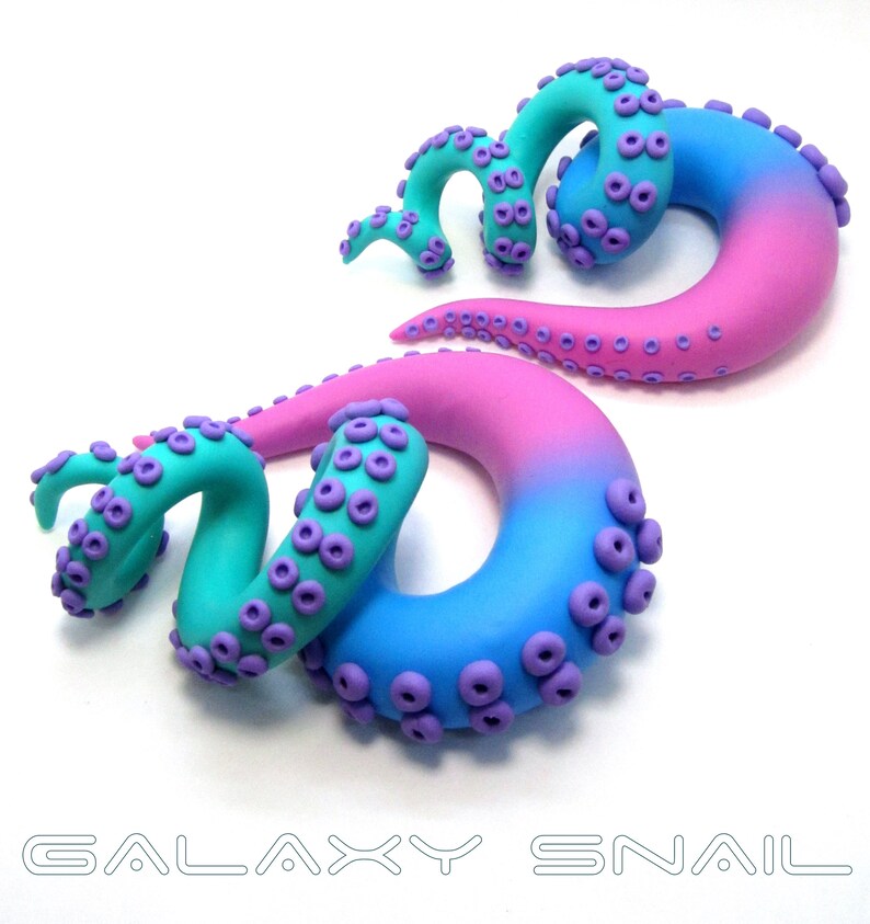 May include: A pair of galaxy-themed octopus ear gauges. The gauges are made of polymer clay and feature a gradient of pink and blue colors. The octopus tentacles are curled and have purple suction cups.