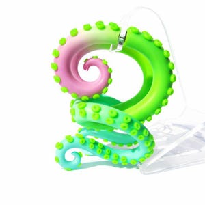 May include: A spiral-shaped sculpture resembling an octopus tentacle with a gradient colour transition from soft pink to vibrant lime green and teal. The tentacle features numerous raised circular suckers along its length and is displayed on a clear stand.