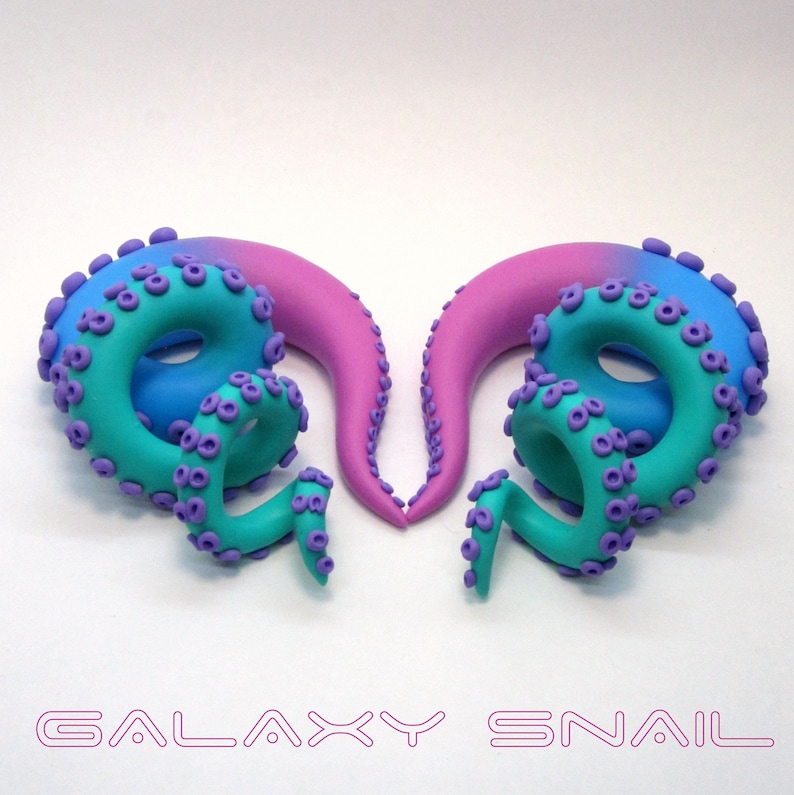 May include: A pair of galaxy snail ear gauges, one is pink to blue ombre and the other is blue to pink ombre. Both have purple tentacles.