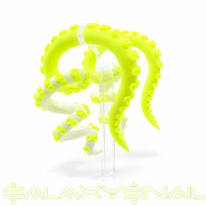 Puede incluir: Joyería corporal en forma de tentáculos de color amarillo neón y blanco. La joyería se exhibe sobre un soporte transparente sobre un fondo blanco. Los tentáculos tienen detalles de ventosas y están curvados y retorcidos.