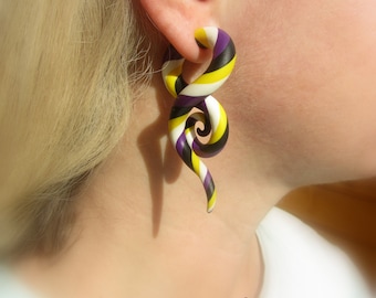 May include: A pair of purple, yellow, and white striped spiral ear gauges. The gauges are made of polymer clay and are shaped like a spiral.