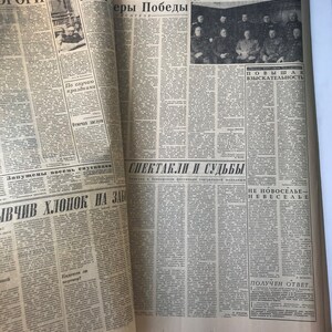 May include: A black and white newspaper with the title "ПРАВДА" and the text "ЗА О И ТР еры Победы" in Russian. The newspaper is folded in half and shows a group of men in uniform. The text "повыШАЯ ВЗЫСКАТЕЛЬНОСТЬ" is also visible.