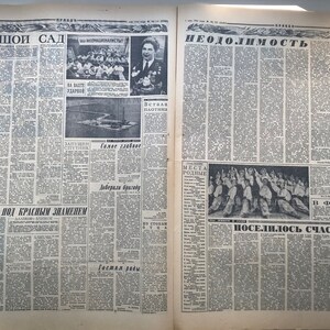May include: A black and white newspaper with the headline "Большой Сад" on the left side and "Неодолимость" on the right side. The newspaper has several articles and photos, including a photo of a group of people in a meeting and a photo of a boat on a river.