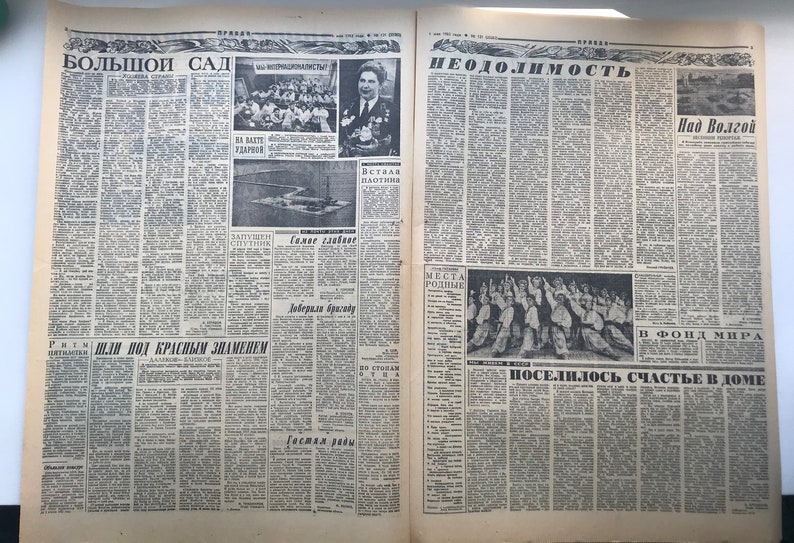 May include: A black and white newspaper with the headline "Большой Сад" on the left side and "Неодолимость" on the right side. The newspaper has several articles and photos, including a photo of a group of people in a meeting and a photo of a boat on a river.