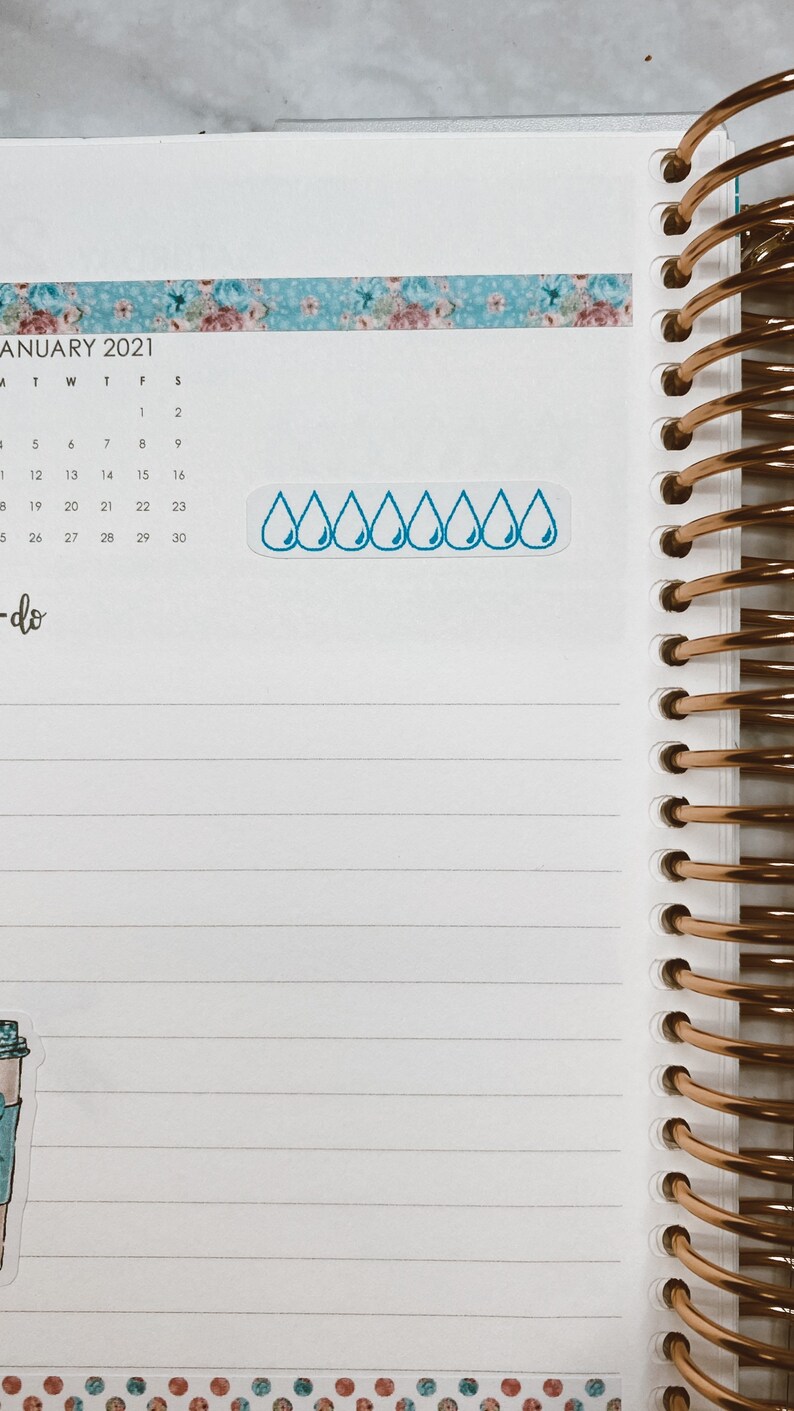 K&ouml;nnte beinhalten: Nahaufnahme einer Seite in einem Planer mit einem blauen, floral gemusterten Washi-Tape und einem Aufkleber mit einer Reihe blauer Regentropfen. Die Seite ist mit Januar 2021 datiert und die Wochentage sind beschriftet. Der Text "to-do" steht am unteren Rand der Seite.