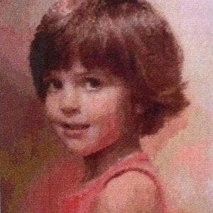 Puede incluir: Un retrato pintado de una niña pequeña con el pelo corto y castaño que lleva un vestido rosa sin mangas. La pintura está realizada en un estilo suave y realista.
