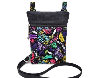 May include: A small black crossbody bag with a zipper closure and a colorful butterfly print. The bag has a black adjustable strap.