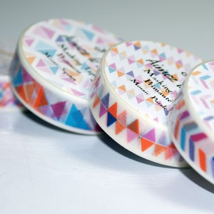 Könnte beinhalten: Vier Rollen farbenfrohes Washi-Tape mit geometrischem Muster. Das Band ist mit "Aimez le Tape" und "Masking Tape" mit einem Mosaik-Puzzle-Design beschriftet.
