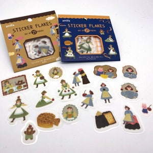 Könnte beinhalten: Ein Set mit 21 Sticker-Flocken mit Illustrationen von Mädchen in Kleidern, Bären, Kuchen und anderen niedlichen Details. Die Sticker sind auf weißem Hintergrund und werden in einer durchsichtigen Plastiktüte geliefert. Die Verpackung ist braun mit weißem Text, der "amifa STICKER FLAKES SET OF 21 PIECES" und "フレークシール ほっこりガーリー カヌレ" lautet.