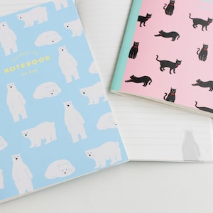 以下が含まれることがあります： 動物のデザインが異なる2冊のノート。最初のノートは、白いホッキョクグマの模様と「The Daily Me Notebook」という文字が書かれた青い表紙。2冊目のノートは、黒い猫の模様が描かれたピンクの表紙です。
