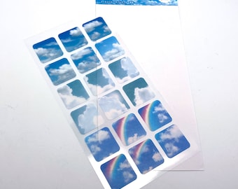 May include: A sheet of 18 stickers featuring a blue sky with white clouds and rainbows. The stickers are arranged in a grid pattern on a clear sheet.
