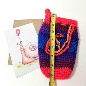 Pochette au crochet aux tons de bijoux colorés avec des signes de la paix et une carte postale originale édifiante comprenant un escargot joyeux et un ballon rouge