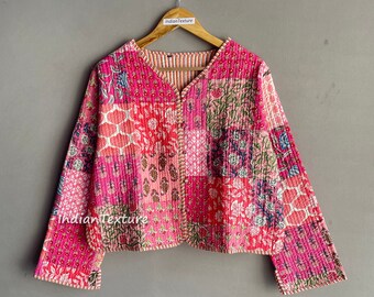 Può includere: Una giacca trapuntata rosa con un design a patchwork floreale. La giacca ha un collo a V e maniche lunghe. Il tessuto è morbido e confortevole.